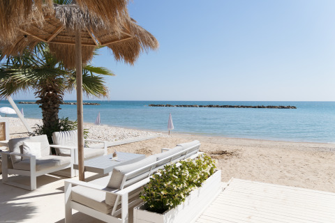 Luxe lodgetenten met comfortabele zithoek en palmbomen bij Villa Alwin Beach Resort, Le Marche.