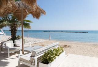 Luxuriöse Strandzelte mit stilvollen Loungemöbeln unter Palmen im Villa Alwin Beach Resort, Le Marche.