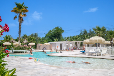 Espace piscine convivial avec parasols et palmiers au Villa Alwin Beach Resort sur la plage de Le Marche.