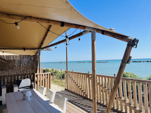 Tienda glamping frente al mar en Villa Alwin Beach Resort con terraza de madera en Le Marche, Italia.