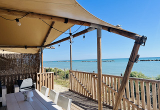 Glamping lodgetent met houten terras aan het strand bij Villa Alwin Beach Resort, Le Marche, Italië.