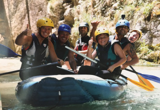 Sei persone con caschi fanno rafting sul fiume, sorridenti, vicino a Villa Alwin Beach Resort nelle Marche.