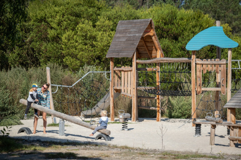 Kinder spielen auf einem Spielplatz mit Holzstrukturen im Huttopia Lagoa de Óbidos Glamping in Portugal.