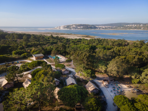 Luchtfoto van Huttopia Lagoa de Óbidos Glamping Portugal met tenten te midden van bos en lagune.