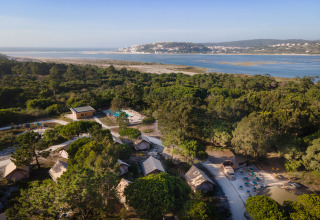 Luchtfoto van Huttopia Lagoa de Óbidos Glamping Portugal met tenten te midden van bos en lagune.