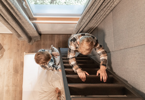Twee kinderen spelen in Wander- & Wellnesshotel Gassner - Boomhut Oostenrijk, bovenaanzicht van bed en trap.