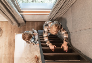 Two children play in Wander- & Wellnesshotel Gassner - Boomhut Oostenrijk, top view of bed and ladder.