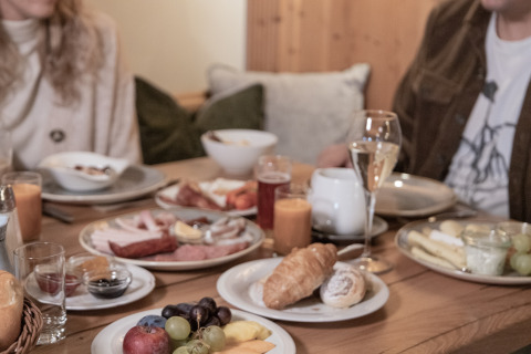 Par nyder en hyggelig morgenmad med frugt, brød og saft i Wander- & Wellnesshotel Gassners boomhut i Østrig.