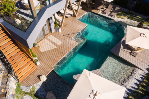 Luxury glamping accommodation at Wander- & Wellnesshotel Gassner featuring a modern pool, deck, and sun loungers.