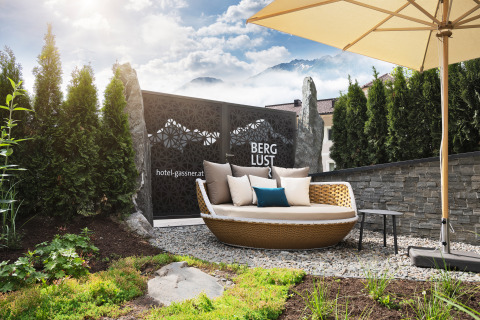 Area relax all'aperto presso Wander- & Wellnesshotel Gassner Boomhut Austria con sdraio, verde e ombrellone.