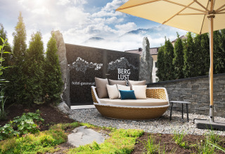 Udendørs afslapningsområde på Wander- & Wellnesshotel Gassner Boomhut Østrig med lounge stol og parasol.