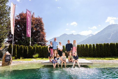 Famiglia vicino alla piscina con sfondo montano presso Wander- & Wellnesshotel Gassner Boomhut Austria.