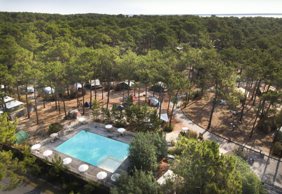 Veduta aerea di Huttopia Lac de Carcans glamping in Aquitania con piscina, tende e ambiente boscoso.