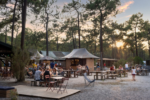 Buiten dineren bij Huttopia Lac de Carcans - Glamping Aquitaine, omgeven door dennenbomen bij zonsondergang.