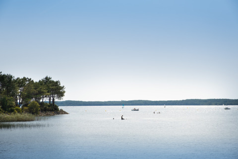 Aussicht auf den See bei Huttopia Lac de Carcans Glamping Aquitaine mit Booten unter blauem Himmel.