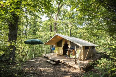 Glamping accommodatie in het bos bij Huttopia Royat - Glamping Auvergne met een tent op een houten vlonder.