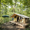 Glamping accommodation in the forest at Huttopia Royat - Glamping Auvergne, featuring a tent on a deck.