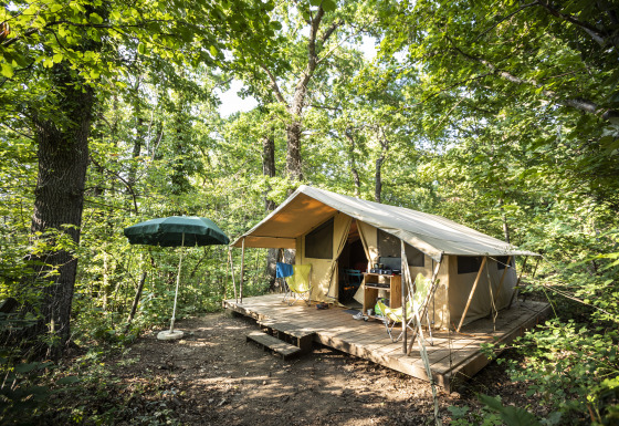 Alojamiento glamping en el bosque de Huttopia Royat - Glamping Auvergne, con tienda sobre plataforma.