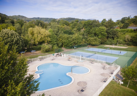 Huttopia Royat - Glamping Auvergne avec piscine et courts de tennis, entouré de forêt verdoyante et de nature.