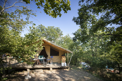 Glamping indkvartering i skoven ved Huttopia Royat - Glamping Auvergne med terrasse, borde og stole.