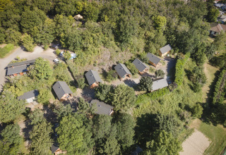 Aerial view of Huttopia Royat - Glamping Auvergne with cozy cabins surrounded by lush green trees.