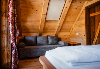 Holzinterieur mit Sofa und Bett im Glamping s'Baumhaus Dörfle - Boomhutten Zwarte Woud.