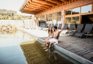 Stel geniet van drankjes bij het buitenzwembad en ligstoelen, s'Baumhaus Dörfle glamping Zwarte Woud.