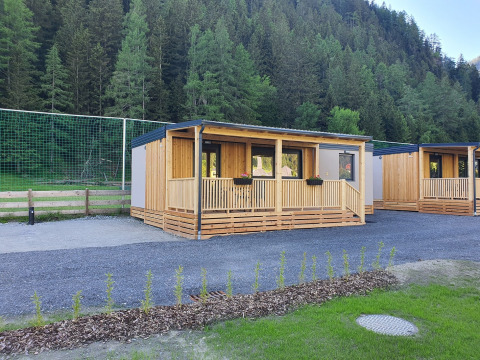 Modern glamping cabins with wooden porch at HochOBEN - Stacaravans Oostenrijk, set amid forested hills.