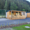 Modern glamping cabins with wooden porch at HochOBEN - Stacaravans Oostenrijk, set amid forested hills.