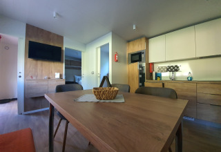 Modern glamping accommodation featuring dining table, kitchen, and TV at HochOBEN - Stacaravans, Austria.