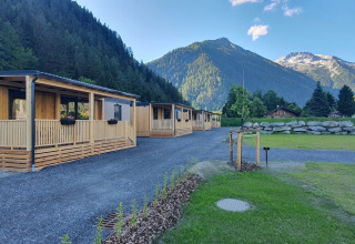 Modernos caravanas de glamping en HochOBEN, Austria, rodeados de montañas y naturaleza bajo cielo azul.