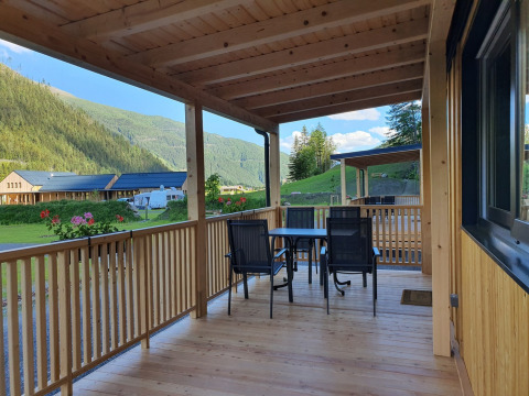 Wooden veranda at HochOBEN - Stacaravans Oostenrijk overlooking mountains and camping area in Austria.