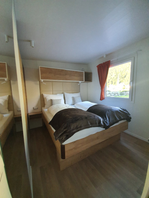 Interieur van glamping accommodatie bij HochOBEN - Stacaravans Oostenrijk met tweepersoonsbed en raam.