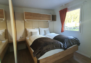 Innenansicht der Glamping-Unterkunft bei HochOBEN - Stacaravans Österreich mit Doppelbett und Fenster.