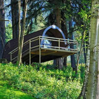 Moderne houten lodge op palen in het groen bij Nature Resort Natterer See - Woodlodges Tirol, perfect voor glamping.