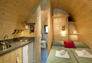 Vista interior del Nature Resort Natterer See Woodlodges Tirol con mobiliario de madera, cama y cocina.