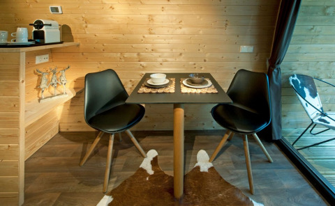 Essbereich im Nature Resort Natterer See - Woodlodges Tirol mit zwei schwarzen Stühlen und kleinem Tisch.