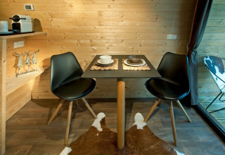Spiseområde i Nature Resort Natterer See - Woodlodges Tirol med to sorte stole og et lille bord.
