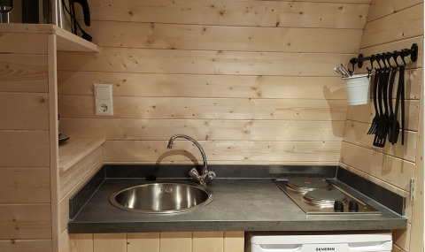 Pequeña cocina de madera con fregadero, fogones y utensilios en Nature Resort Natterer See Woodlodges Tirol.
