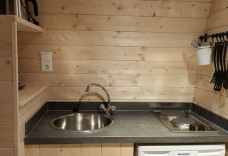 Piccola cucina in legno con lavello, fornelli e utensili al Nature Resort Natterer See Woodlodges Tirol.