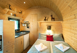 Cozy wood lodge featuring a double bed, kitchenette, and rustic decor at Nature Resort Natterer See Tirol.