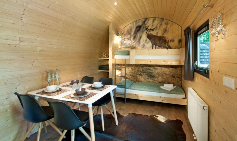 Innenraum einer Woodlodge im Nature Resort Natterer See in Tirol mit Etagenbett und Esstisch für vier.