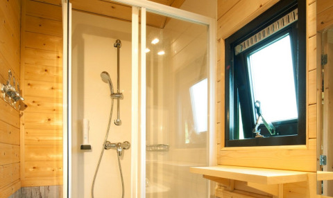 Ducha moderna y paredes de madera en alojamiento glamping Nature Resort Natterer See - Woodlodges Tirol en Austria.