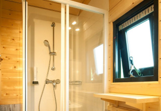 Doccia moderna e pareti in legno in glamping Woodlodges Tirol presso Nature Resort Natterer See in Austria.