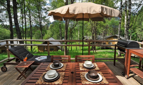 Terrazza in legno con tavolo, ombrellone e barbecue presso Nature Resort Natterer See - Woodlodges Tirol.