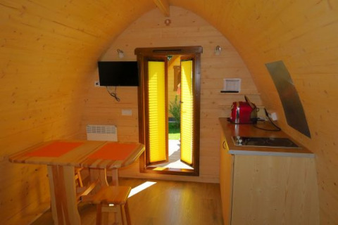 Vista interior de una acogedora cabaña de madera en Camping Putterersee, Austria, con mesa y cocina pequeña.