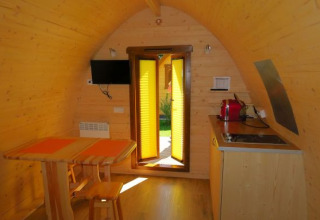 Indvendig udsigt over en hyggelig træ-pod på Camping Putterersee i Østrig med spiseplads og lille køkken.