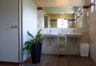 Modernes Badezimmer mit zwei Waschbecken, großem Spiegel und Pflanze im Camping Putterersee, Österreich.