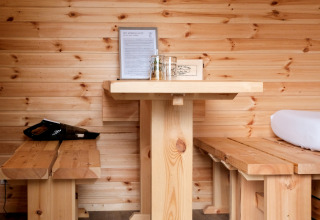 Acogedor interior de madera con mesa y bancos en Natuurpark Camping Prinzenholz, Schleswig-Holstein.