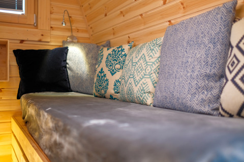 Hyggelig siddeplads med farverige puder i en træbeklædt hytte ved Natuurpark Camping Prinzenholz.